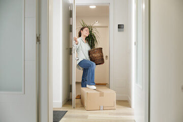 Young woman entering the door of her new house. She is a homeowner. New beginnings. New decor,...
