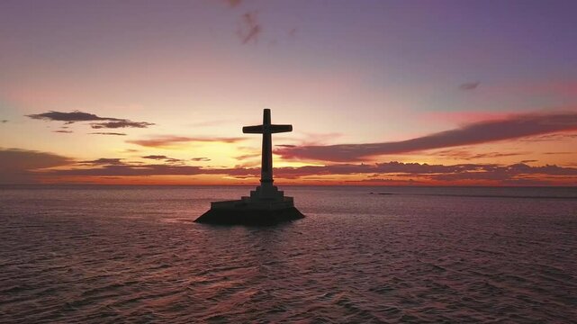 Aerial drone establishing of the Sunken Cemetery cross at Camiguin Island, Philippines, during a stunning sunset over the ocean