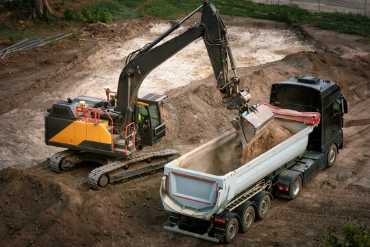 Excavator loading dirt into a truck, view from above
