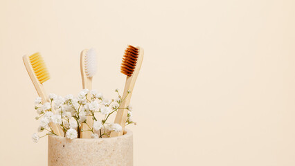 Bamboo toothbrushes set with flowers on beige background with copy space. Eco friendly product,...