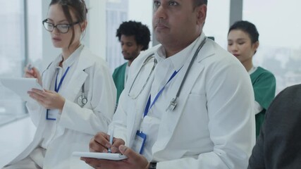 Tilt up shot of diverse doctors meeting at medical training in modern clinic