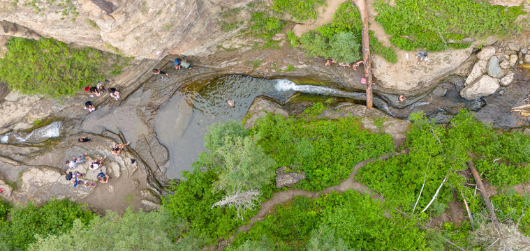 Drone view above people sliding in the Devils Bathtub waterfall and pool in Spearfish Canyon, South Dakota