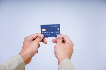 A hand holding a modern credit card with a microchip against a plain background.