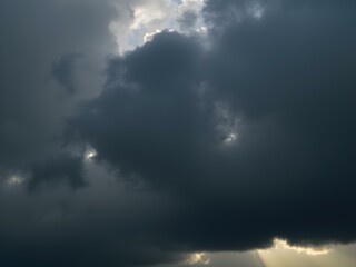 Obraz premium A moody sky with heavy gray clouds and soft sunlight peeking through, creating a dramatic contrast between light and shadow 