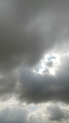 Obraz premium A moody sky with heavy gray clouds and soft sunlight peeking through, creating a dramatic contrast between light and shadow 