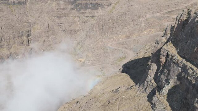 Slow aerial reveal of Sani Pass on clear winter day, mist pushes up from lowlands below