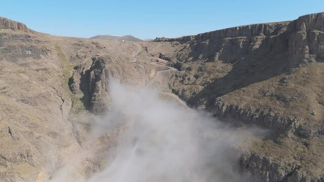 Wid aerial rise over Sani Pass and Sani Top village on clear winter day