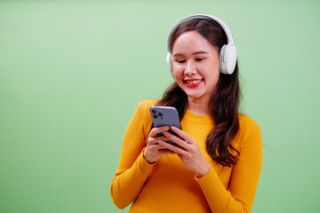 Young woman smiling with headphones and using smartphone.