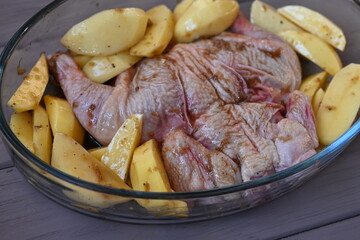 marinated chicken  and potatoes in sauce in a dish before baking, the texture of potatoes and meat cooked for dinner 