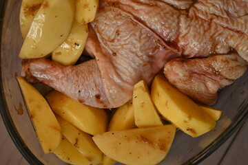 marinated chicken  and potatoes in sauce in a dish before baking, the texture of potatoes and meat cooked for dinner 
