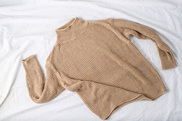Soft sweater of beige luxury natural mix wool lying on white fabric background. Autumn and winter pure wool female clothing.