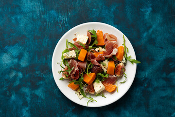 Autumn salad with Jamon blue cheese and figs butternut pumpkin rocket on white plate food top view