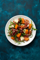 Autumn salad with Jamon blue cheese and figs butternut pumpkin rocket on white plate