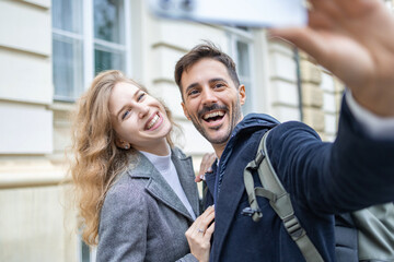 Handsome guy holding the phone in his hand and smiling and posing for a selfie with his girlfriend