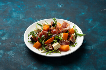 Autumn salad with Jamon blue cheese and figs butternut pumpkin rocket on white plate food close up