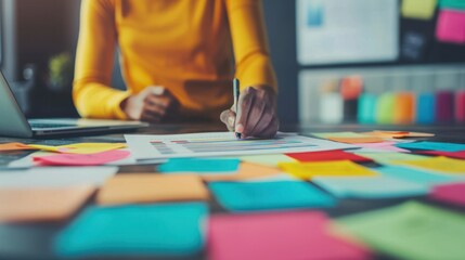 Obraz premium Person analyzing data chart surrounded by colorful sticky notes on a desk during a planning session