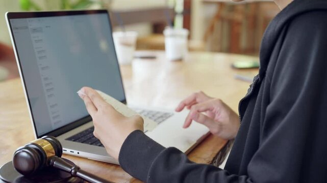 A person is using a laptop and a cell phone at the same time. The laptop is open to a webpage with a message on it. The person is looking at the cell phone, which is on the table
