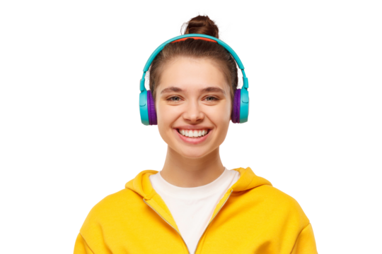 Young smiling teenage girl, wearing yellow hoodie, listening to music in wireless headphones