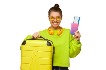 Portrait of young happy girl in neon green sweatshirt and glasses, holding travel suitcase and passport with airplane tickets in hands