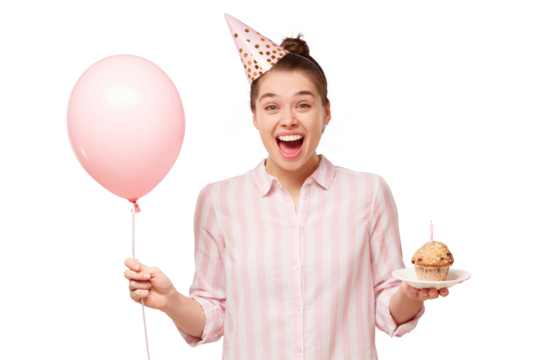 Young excited girl wearing birthday hat, holding balloon and plate with cake, feeling happy and satisfied with surprise