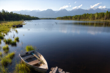 Obraz premium Landscape with mountains, lake and old wooden boat