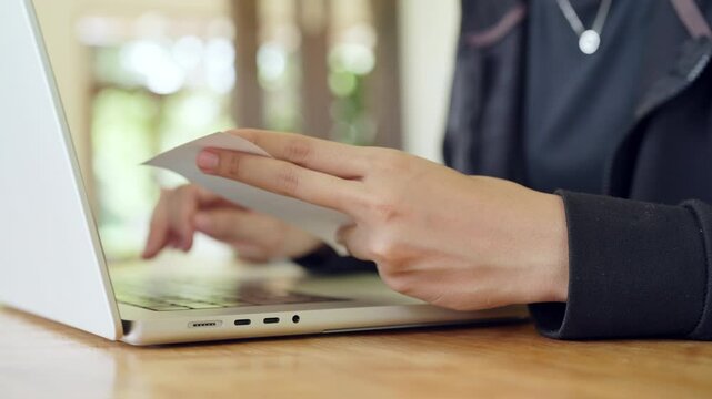 A person is using a laptop to clean a credit card. Concept of practicality and efficiency, as the person is taking care of a necessary task in a timely manner