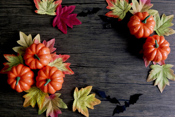 Festive autumn decoration, Halloween background, top view orange pumpkins with leaves and bat on a wooden background. greetings Halloween autumn celebration.