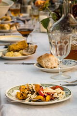 close-up of food on a large festive outdoor table with a beautiful decoration of flowers and a white tablecloth in the middle of mountains