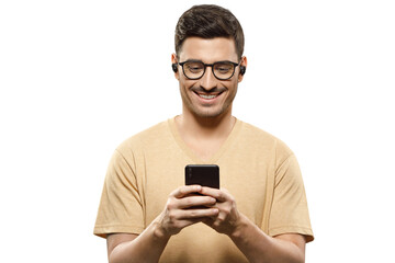 Portrait of young handsome man wearing beige t-shirt, glasses and wireless earphones, looking at phone screen with smile