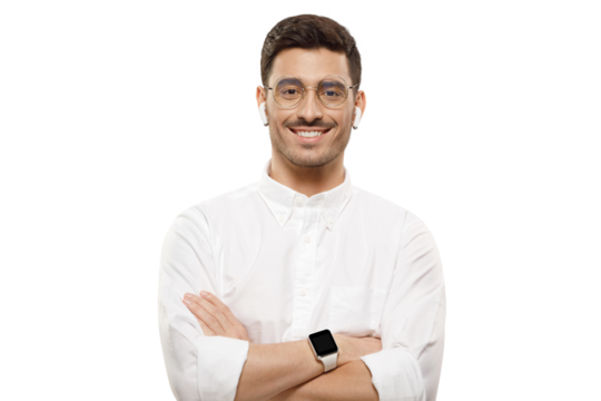 Young man wearing white shirt, glasses and wireless earphones, holding arms crossed, looking at camera with happy confident smile