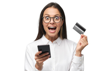 Portrait of excited young woman with mouth open, holding credit card, using mobile phone with banking app