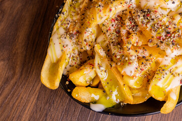 Patate fritte e condite con salsa agli agrumi, pepe nero, pepe verde e pepe rosa servite come antipasto in una braceria