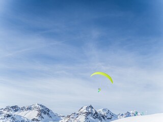 Paraglider over snowy mountains at Serre Chevalier