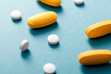 White tablets and yellow pills on a blue background.
