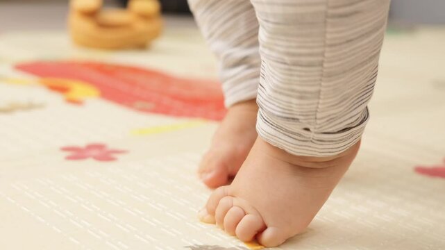 Soft baby indoors barefoot with tender feet and toes moving legs having muscle tone during early stages of growth