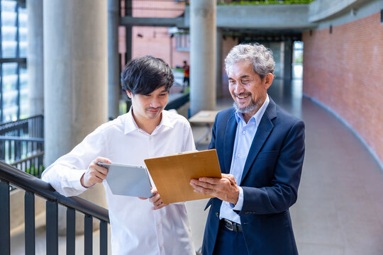 Asian senior professor is giving advice  to the college student on the research thesis while sitting in the university faculty for education, academic and business concept