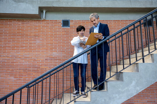 Asian senior professor is giving advice  to the college student on the research thesis while sitting in the university faculty for education, academic and business concept