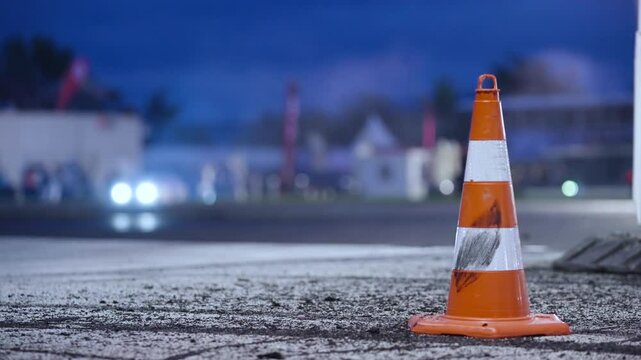 Professional race car passing behind the road cone on race track at night 4K
