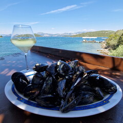Mussels with glass of white wine on a beach