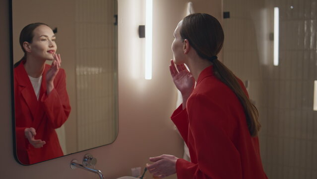 Girl reflection admiring beauty in soft bathroom light. Beautiful woman adjust