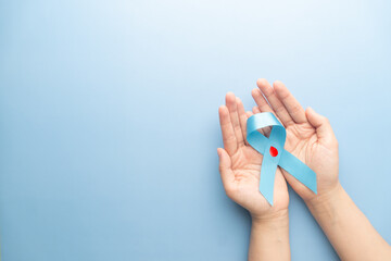World diabetes day awareness concept. Hands holding blue ribbon with blood drop symbol for...