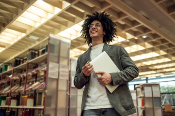 Curly-haired young man in eyeglasses in the library