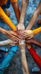 Close-up of young people's hands together in teamwork on a grey background, top view. Conceptual photo for teamwork, community support, or friendship. 