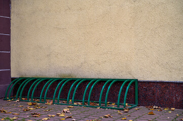 Fototapeta premium Fragment of empty street city, gray yellow wall of building and pavement. Bicycle parking. Mockup or background for creativity. Place for advertising, banner, billboard, announcement, poster.