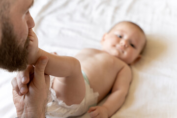 Dad kissing newborn child while taking care of baby alone at home