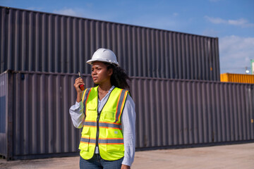 Engineer or dockworker working in the construction container dock yard checking and inspection containers data on computer program environment is container shipping Logistics business concept.