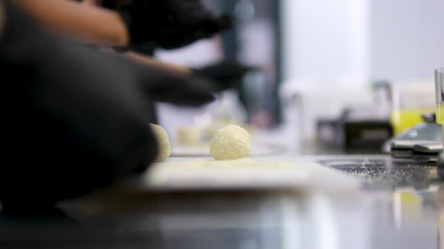 Lifestyle. Traditional south american food. Closeup view of a woman hands making chipa cheese balls with dough, and placing them in a baking dish. cheese balls cooking