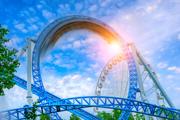 Amusement trolley motion blur speed effect makes circle loop turns upside down, roller coaster. Sunshine sunset glare clouds sky