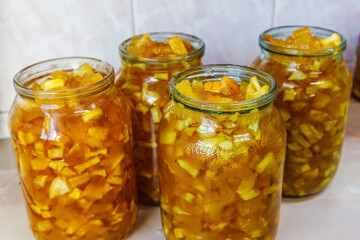 Glass jars with apple jam on kitchen table before closing with lids for preservation.