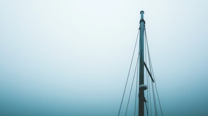 Obraz premium Abstract minimalist sail mast emerging from a mysterious foggy horizon, evoking tranquility and solitude in a serene seascape.